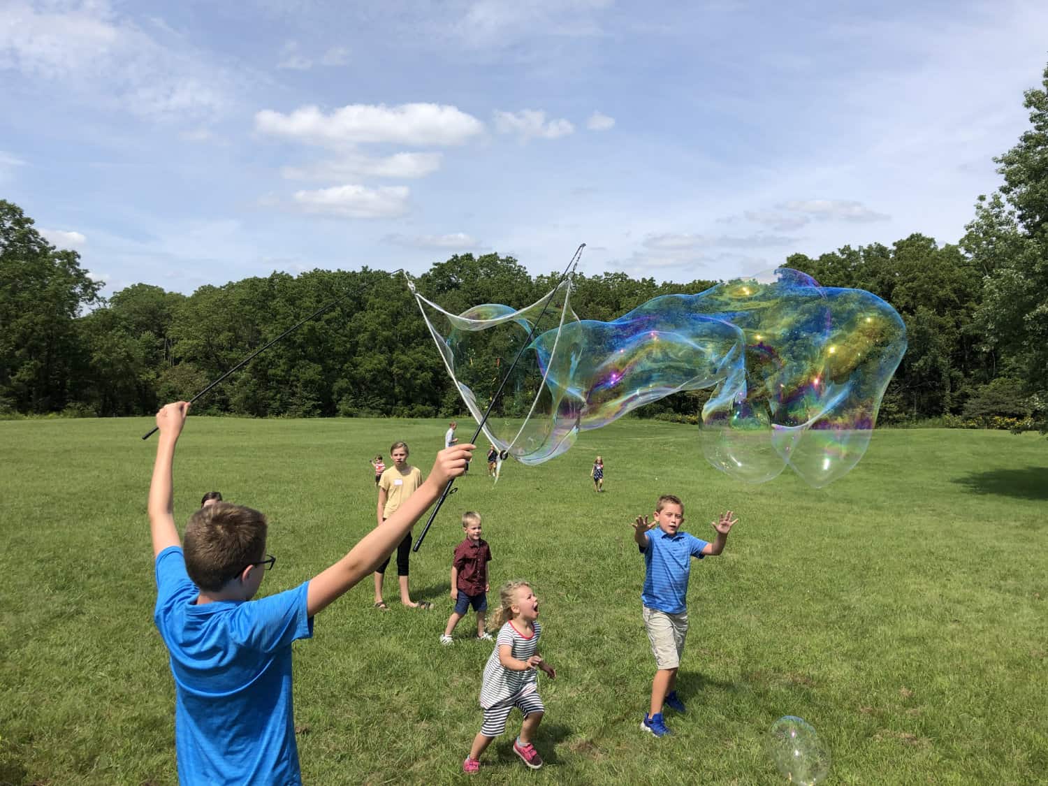 First Congo church children playing with huge bubble machines in field